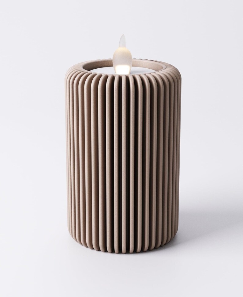 May include: A beige, cylindrical LED candle with a vertical ribbed design. The top features a recessed area with a flickering, flame-shaped light. The candle is designed to mimic the appearance of a real candle.