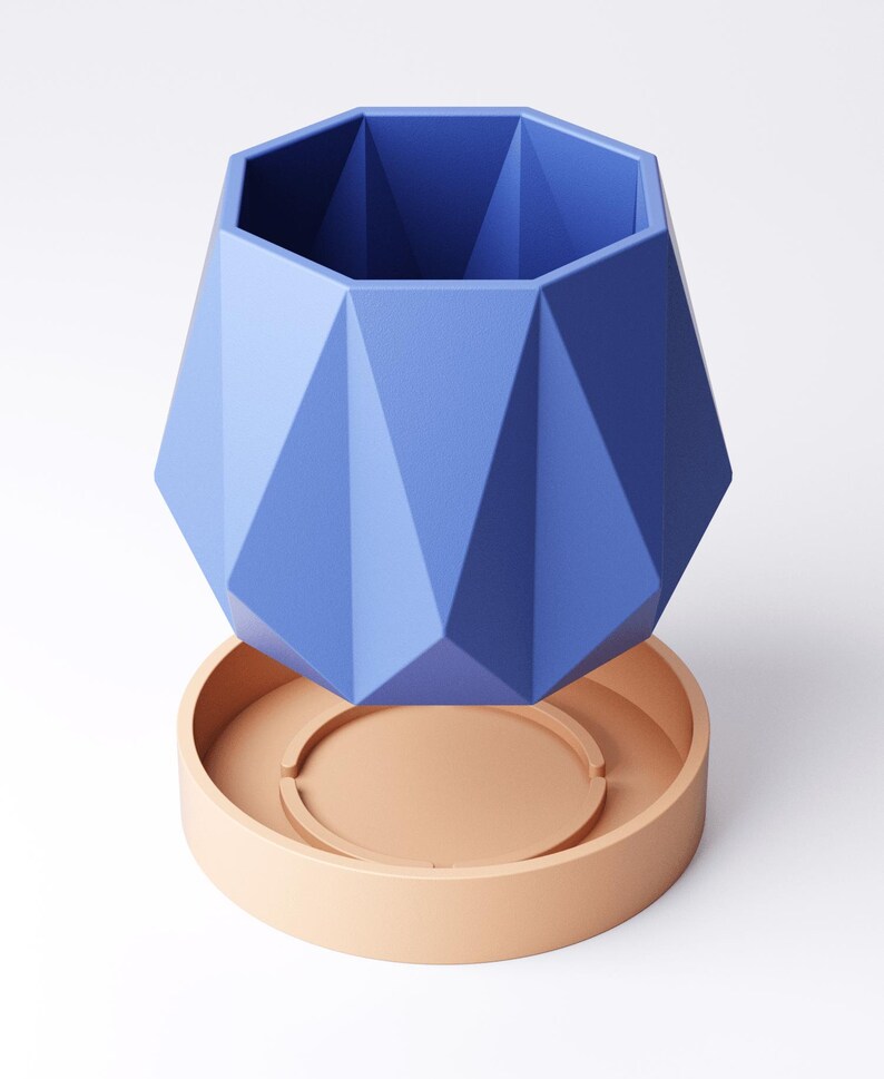 May include: A geometric, blue planter with a matching peach-coloured saucer. The planter has a faceted design, creating a modern and stylish look. This decorative piece is suitable for indoor plants and adds a pop of colour to any room.