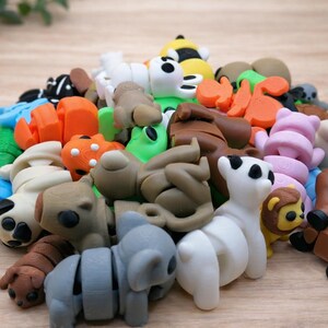 Op de afbeelding: Een verzameling kleurrijke dierfiguren-gummen, waaronder panda's, koala's en leeuwen. De gummen zijn in bruin, wit, oranje en groen en liggen op een lichtbruin houten oppervlak.