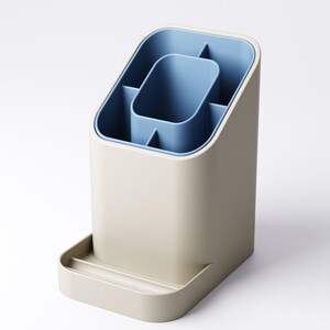May include: A beige and blue desk organizer with multiple compartments. The organizer has a rectangular base with a small tray at the bottom. The interior is blue, with a central rectangular section and several smaller compartments. The exterior is a neutral beige color.
