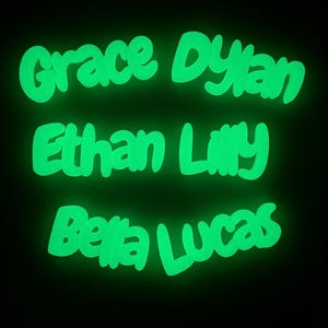 May include: Bright green, glowing names against a black backdrop. The names "Grace Dylan", "Ethan Lilly", and "Bella Lucas" are written in a whimsical font. Suitable for personalised room decorations or presents.