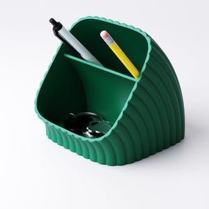 May include: A dark green desk tidy with a scalloped edge design. The organiser has three compartments and contains a black pen, a grey pen, a yellow pencil, and a set of keys. The organiser is made of a solid material.