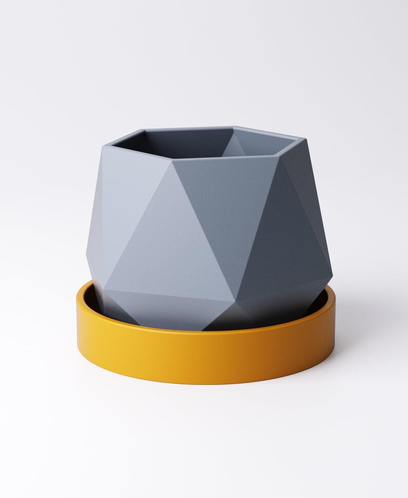May include: A geometric, gray planter with a faceted design sits atop a bright yellow saucer. The planter has a hexagonal opening and a modern, minimalist aesthetic. This decorative piece is suitable for small plants or succulents.