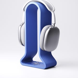 Peut inclure: Un support de casque bleu avec un design incurv&eacute;, tenant une paire de casques argent&eacute;s et blancs. Le support a une texture rainur&eacute;e et un petit plateau avec des trombones argent&eacute;s. Les &eacute;couteurs sont modernes et &eacute;l&eacute;gants.