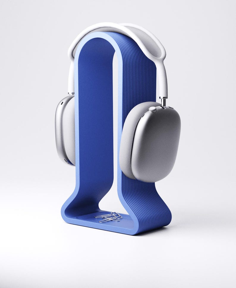 Peut inclure: Un support de casque bleu avec un design incurv&eacute;, tenant une paire de casques argent&eacute;s et blancs. Le support a une texture rainur&eacute;e et un petit plateau avec des trombones argent&eacute;s. Les &eacute;couteurs sont modernes et &eacute;l&eacute;gants.