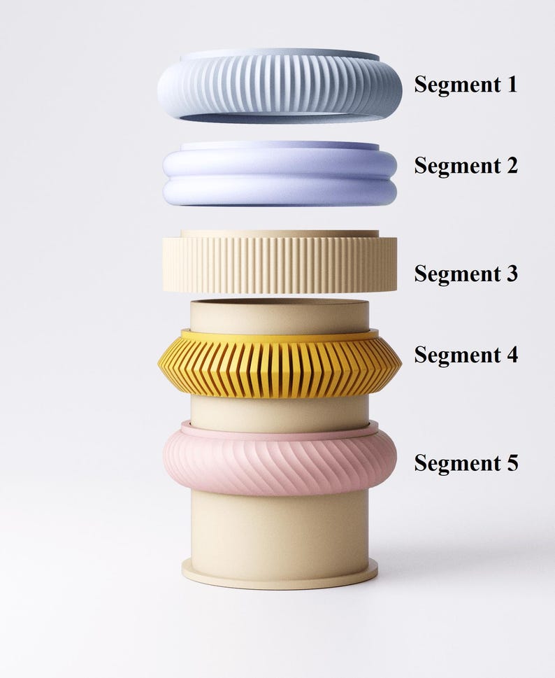 K&ouml;nnte beinhalten: Ein Stapel aus f&uuml;nf farbenfrohen, segmentierten Armb&auml;ndern in Blau-, Lavendel-, Beige-, Gelb- und Rosat&ouml;nen. Jedes Armband hat ein einzigartiges Design mit gerippten, geschwungenen und geometrischen Mustern. Die Segmente sind mit 1 bis 5 beschriftet.