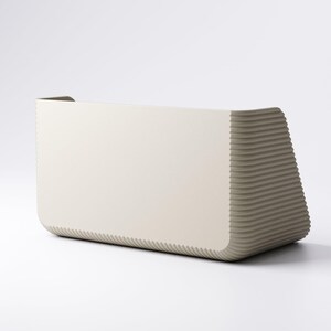 May include: A modern, rectangular, off-white planter with a textured, ribbed design on the sides. The planter has a curved front and a solid, smooth back. The overall shape is geometric and minimalist.