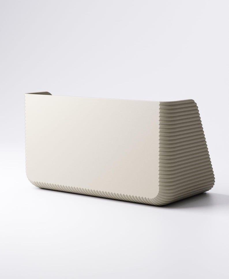 May include: A modern, rectangular, off-white planter with a textured, ribbed design on the sides. The planter has a curved front and a solid, smooth back. The overall shape is geometric and minimalist.