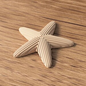 May include: A light-colored wooden starfish with carved lines on each point. The starfish is lying on a wooden surface with visible grain. The starfish is a decorative item.