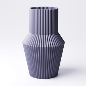 Pu&ograve; includere: Un vaso color lavanda con un design a coste. Il vaso ha una parte superiore cilindrica e una base conica svasata. Le nervature verticali creano una superficie strutturata. Il vaso &egrave; un oggetto decorativo.