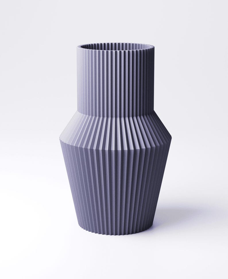 Pu&ograve; includere: Un vaso color lavanda con un design a coste. Il vaso ha una parte superiore cilindrica e una base conica svasata. Le nervature verticali creano una superficie strutturata. Il vaso &egrave; un oggetto decorativo.