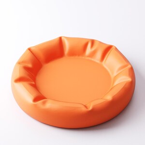 May include: A round, orange tray with a slightly raised, pleated edge. The tray has a smooth, matte finish and a shallow interior. The design is simple and modern, suitable for serving or display.