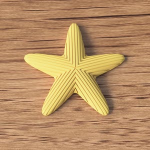 May include: A yellow starfish with textured lines, resting on a wooden surface. The starfish has five points and a slightly rounded shape. The wood grain is visible in the background.