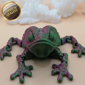 May include: A green and purple iridescent frog figurine with articulated limbs. The frog has a textured surface and is posed with its eyes closed.