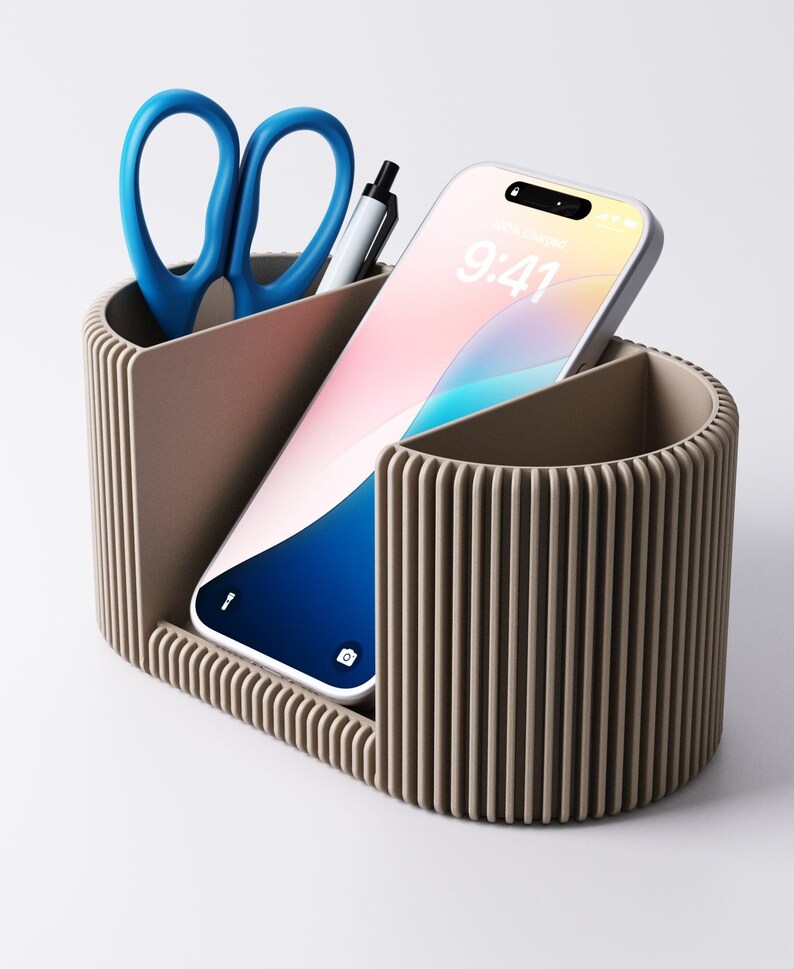 May include: A taupe desk tidy with three sections. One contains blue scissors and a pen, another a smartphone showing 9:41, and the third is empty. The organiser has a ribbed design.