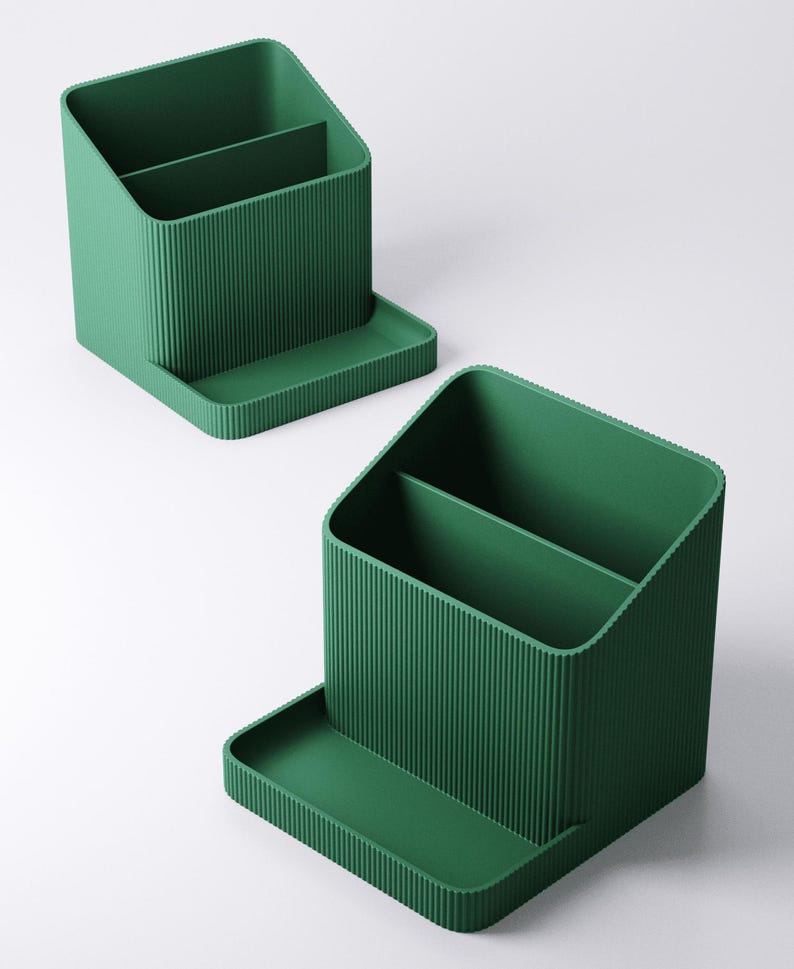 May include: Two green desk organizers with a ribbed texture. Each organizer has two compartments and a small tray. The organizers are made of a solid green material and are designed to hold pens, pencils, and other office supplies.