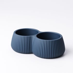 May include: A navy blue, double-bowl planter with a ribbed exterior. The two connected bowls have a rounded, bulbous shape and are set against a white background. The planter is made of a solid material.