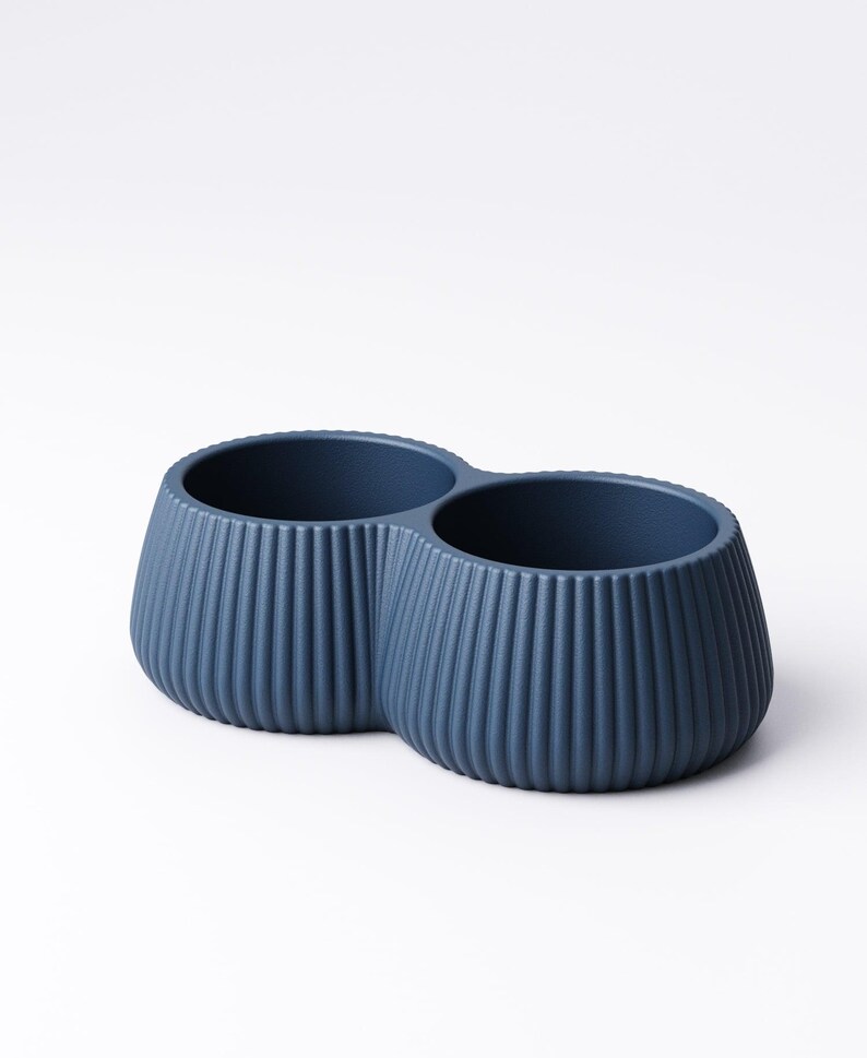May include: A navy blue, double-bowl planter with a ribbed exterior. The two connected bowls have a rounded, bulbous shape and are set against a white background. The planter is made of a solid material.