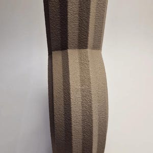 May include: A tall, textured vase in shades of brown and tan. The vase has a unique, geometric design with vertical ridges and a star-shaped top. The vase is approximately 12 inches tall.