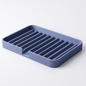 May include: A blue rectangular dish drying rack with a ribbed design. The rack has raised edges and a series of parallel ridges across the surface for draining dishes. The rack is made of a solid, durable material.