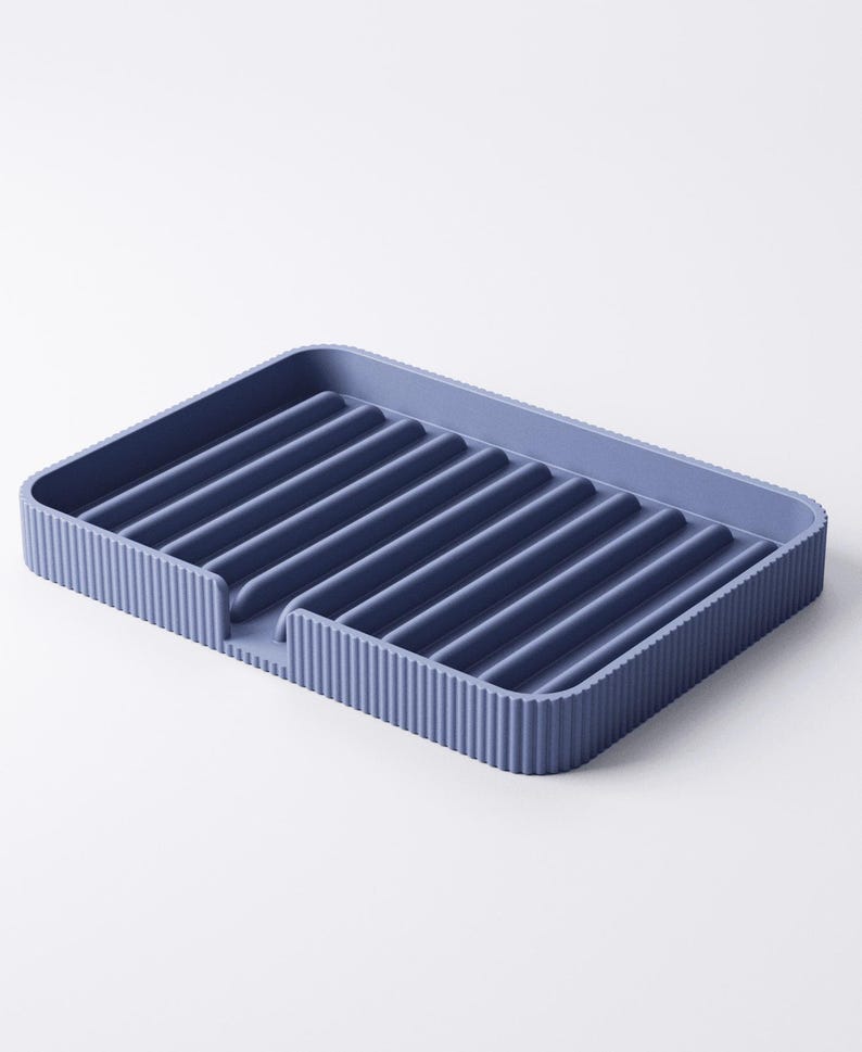 May include: A blue rectangular dish drying rack with a ribbed design. The rack has raised edges and a series of parallel ridges across the surface for draining dishes. The rack is made of a solid, durable material.