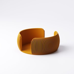 May include: Mustard yellow, open-ended, curved container with vertical ridged detailing. The modern design features a rounded shape with a flat base and smooth interior. The container is made of a solid material and is set against a white background.
