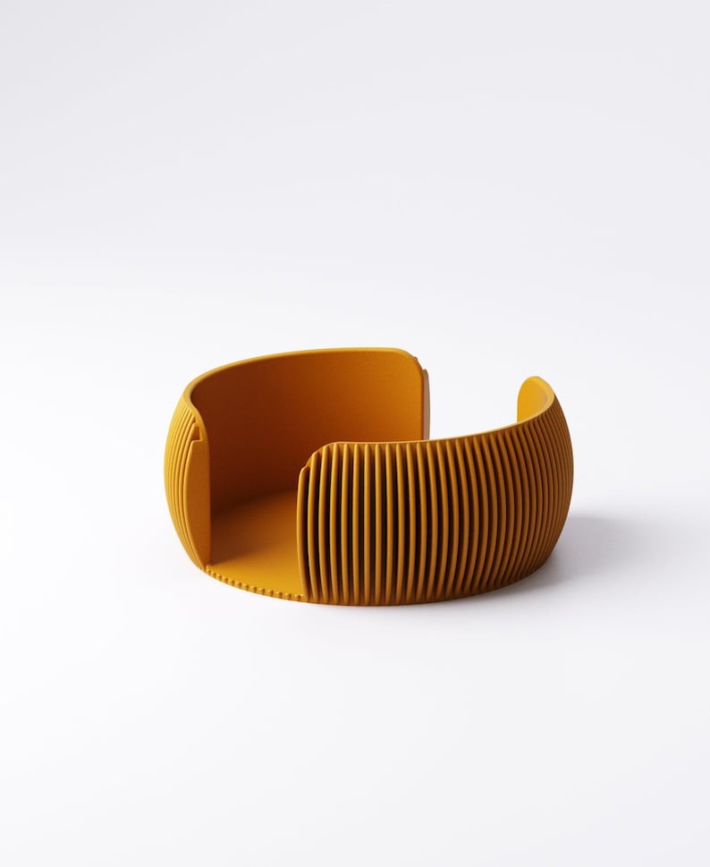 May include: Mustard yellow, open-ended, curved container with vertical ridged detailing. The modern design features a rounded shape with a flat base and smooth interior. The container is made of a solid material and is set against a white background.