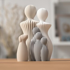 Puede incluir: Un conjunto de figuras familiares de madera. Cada figura est&aacute; hecha de madera clara con ranuras verticales, creando un efecto rayado. La figura m&aacute;s alta mide aproximadamente 25 cm de altura.