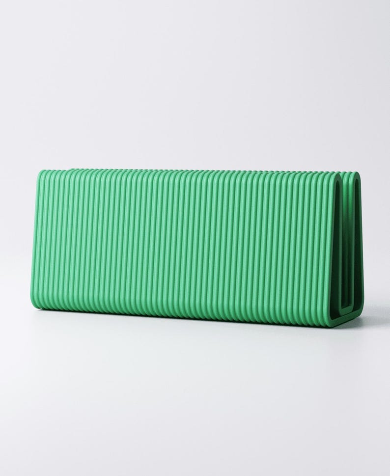 May include: A rectangular, bright green object with a ribbed texture. The object has a folded design, with rounded corners. The color is a vibrant, solid green, and the surface has vertical ridges. The object is set against a plain white background.
