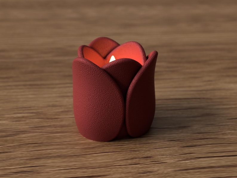 May include: A burgundy-colored tulip-shaped candle holder with a textured surface. The interior glows with a warm orange light, and a small white candle is visible inside. The candle holder is placed on a wooden surface.
