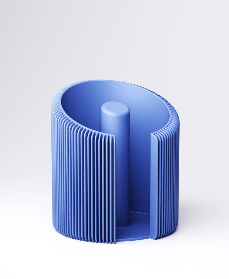 May include: A blue cylindrical object with vertical ribbed detailing. The design features a central, solid cylinder and a curved outer wall. The object is made of a solid, matte material and is set against a white background.