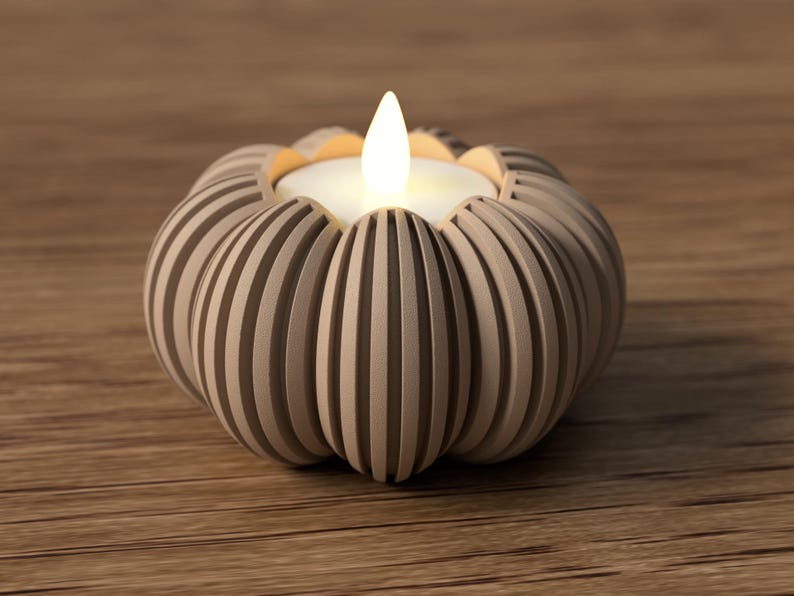 May include: A beige, pumpkin-shaped candle holder with vertical grooves. The candle holder has a white candle with a flickering flame. The candle holder is on a wooden surface.