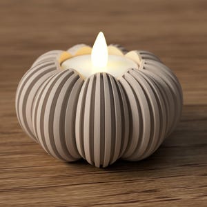 May include: A gray, pumpkin-shaped candle holder with vertical grooves. The candle holder has a white candle with a flickering flame. The candle holder is on a wooden surface.