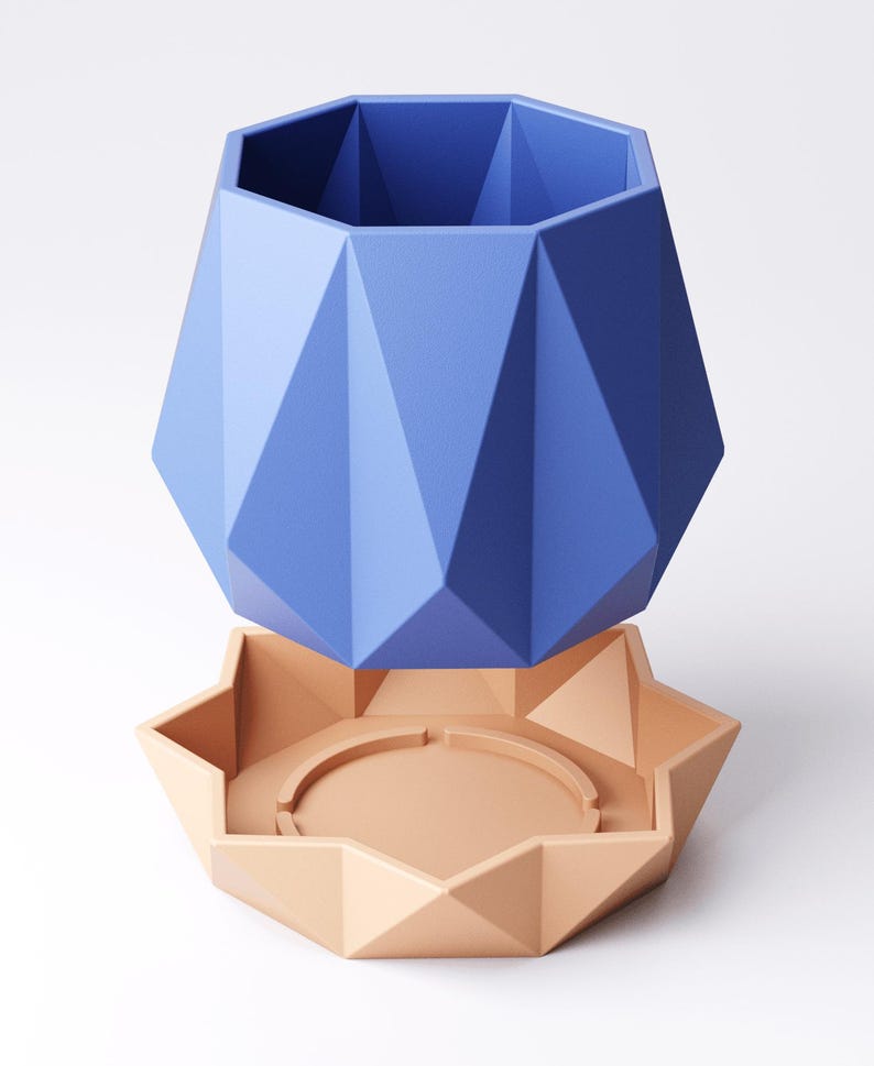 May include: A blue geometric planter and a peach-coloured saucer. The planter has a faceted design and a wide opening. The saucer has a star-like shape with a circular indentation. The planter and saucer are made of a solid material. The planter is approximately 15 cm tall.