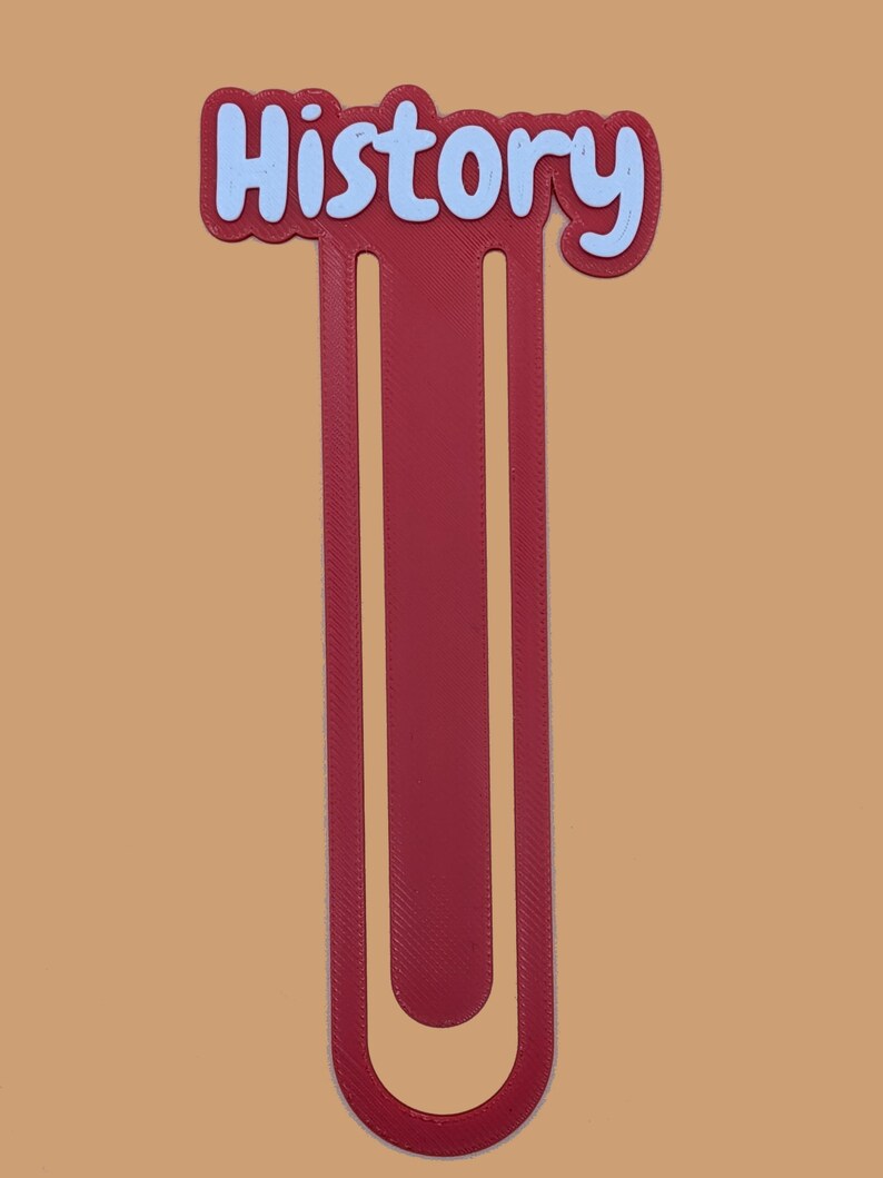 May include: A maroon bookmark featuring a U-shaped design with a textured surface. The top section displays the word History in light blue, rounded, bubble-style lettering with a dark maroon outline, set against a solid, plain background.
