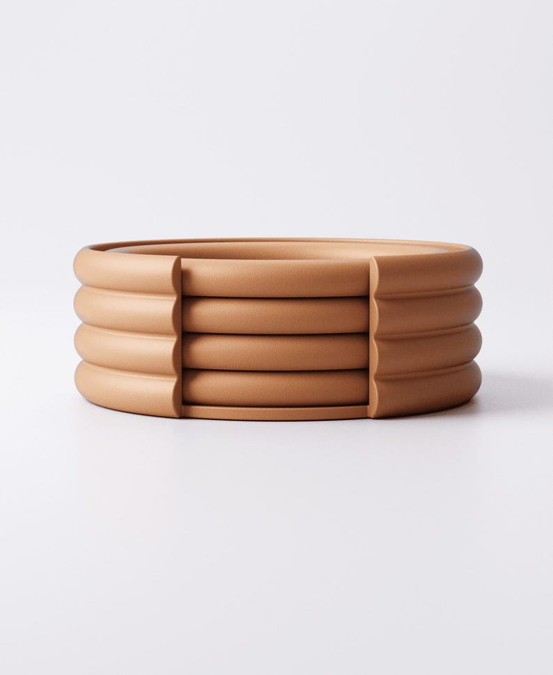Puede incluir: Un conjunto de cuatro posavasos redondos de cer&aacute;mica color terracota. Cada posavasos tiene un borde redondeado y estriado. Los posavasos est&aacute;n apilados, con un peque&ntilde;o espacio entre cada uno. Fondo blanco. Miden aproximadamente 12 cm de di&aacute;metro.