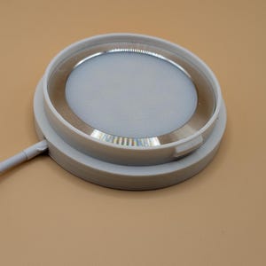 K&ouml;nnte beinhalten: Eine runde, wei&szlig;e LED-Leuchte mit einem silberfarbenen Innenring. Die Leuchte hat ein flaches, kreisf&ouml;rmiges Design und ein wei&szlig;es Netzkabel, das sich von der Seite erstreckt. Die Leuchte ist f&uuml;r Einbauanwendungen konzipiert.