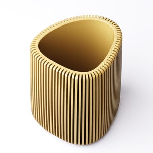 May include: A light brown, open-top container with a unique design. The container has a rounded, oblong shape with vertical, evenly spaced wooden slats forming the sides. The interior is a solid light brown color. The container is set against a white background.