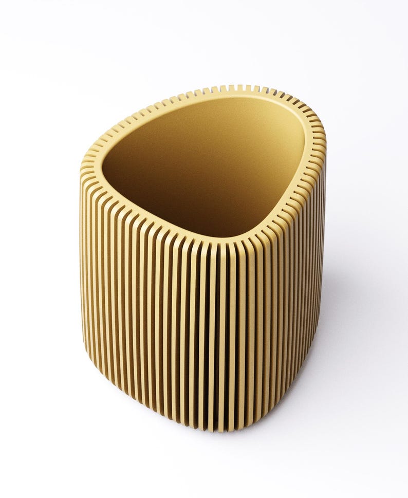May include: A light brown, open-top container with a unique design. The container has a rounded, oblong shape with vertical, evenly spaced wooden slats forming the sides. The interior is a solid light brown color. The container is set against a white background.