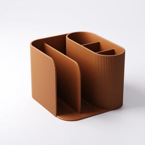May include: A brown desk organizer with a ribbed texture. The organizer has multiple compartments, including a section for files and a section with dividers for pens or small items. The design is modern and minimalist.