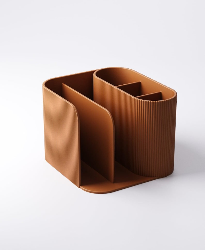 May include: A brown desk organizer with a ribbed texture. The organizer has multiple compartments, including a section for files and a section with dividers for pens or small items. The design is modern and minimalist.