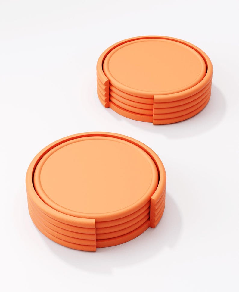 May include: Two stacks of orange coasters. Each coaster is round with a raised edge and a flat center. The coasters are made of a solid material and have a smooth surface. The coasters are designed to protect surfaces from drink rings.