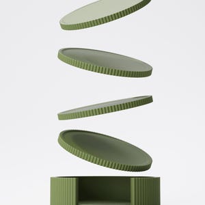 May include: A set of four olive green, oval-shaped trays and a matching base. The trays have a ridged edge and appear to be floating above the base. The base is a rectangular box with a matching ridged design. The background is plain white.