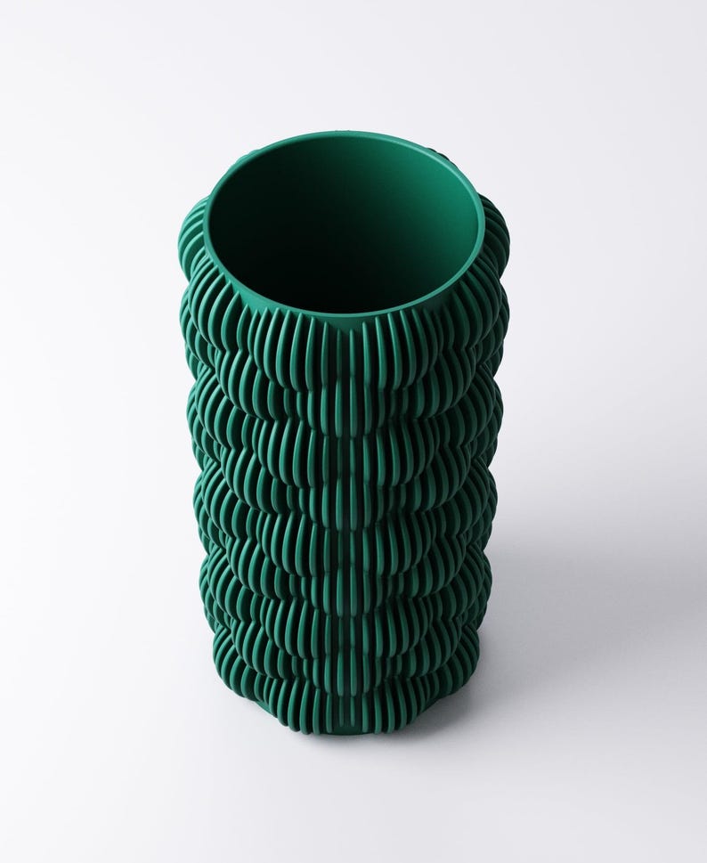 May include: A tall, cylindrical vase in a deep forest green hue. The vase features a textured, ridged design that wraps around the entire body. The opening at the top is circular, and the vase stands on a white background.