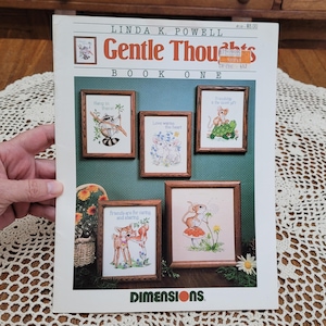 May include: A craft pattern booklet titled Gentle Thoughts Book One by Linda K. Powell, featuring five cross-stitch designs of animals in wooden frames, including a raccoon, mice, a turtle, a deer, and a squirrel, with the Dimensions logo at the bottom.