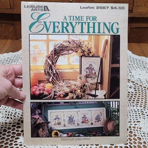 May include: A craft leaflet titled "A Time For Everything" by Leisure Arts. The cover features a fall-themed cross-stitch design with a wreath, framed artwork, and the text "A Time For Everything".