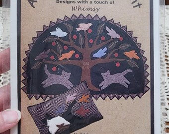 May include: A craft pattern packet titled All Through the Night featuring a tree with birds and two cats, plus a plaid pillow design. Text includes # 309 Cat's Caper, Finished Sizes: Penny Rug 26 1/2" x 18", Pillow: 17" x 11", and ©2003.