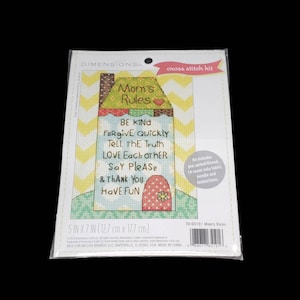May include: Cross stitch kit featuring a house with the words "Mom's Rules" and a list of rules: Be Kind, Forgive Quickly, Tell the Truth, Love Each Other, Say Please, & Thank You, Have Fun. The kit includes pre-sorted thread, 14 count Aida fabric, needle and instructions. 5 inches by 7 inches (12.7 cm by 17.7 cm).