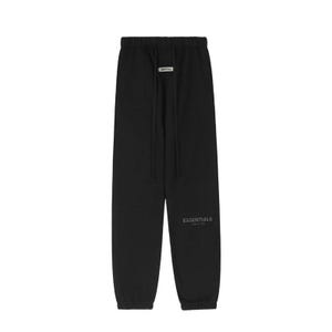 May include: Black sweatpants with a drawstring waist and the word "ESSENTIALS" printed on the left leg. The pants have a relaxed fit and a small rectangular tag near the drawstring.