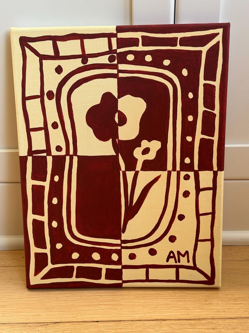 Puede incluir: Un cuadro rectangular sobre lienzo con un dise&ntilde;o dividido en granate oscuro y crema. La composici&oacute;n muestra un motivo floral estilizado dentro de un borde decorativo de puntos y rect&aacute;ngulos. Las letras AM est&aacute;n pintadas en la esquina inferior derecha.